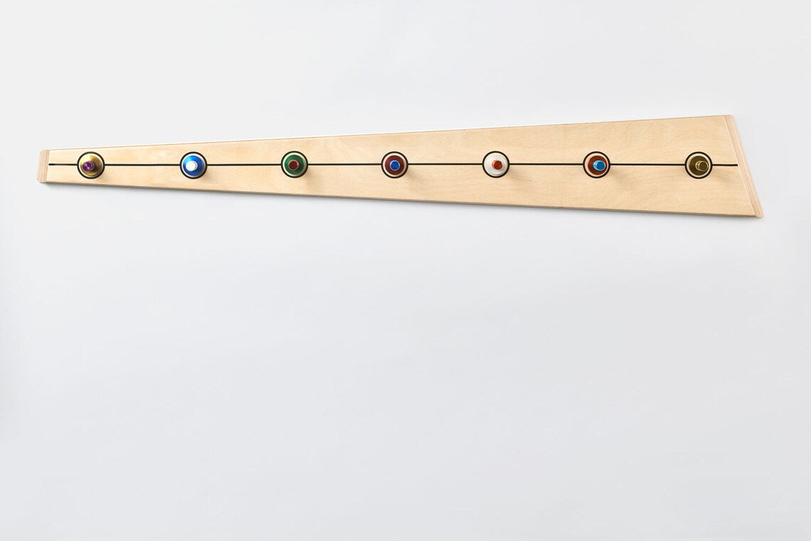 Vibrant rainbow-colored aluminum hooks on a handcrafted wooden base, enhancing entryway decor.